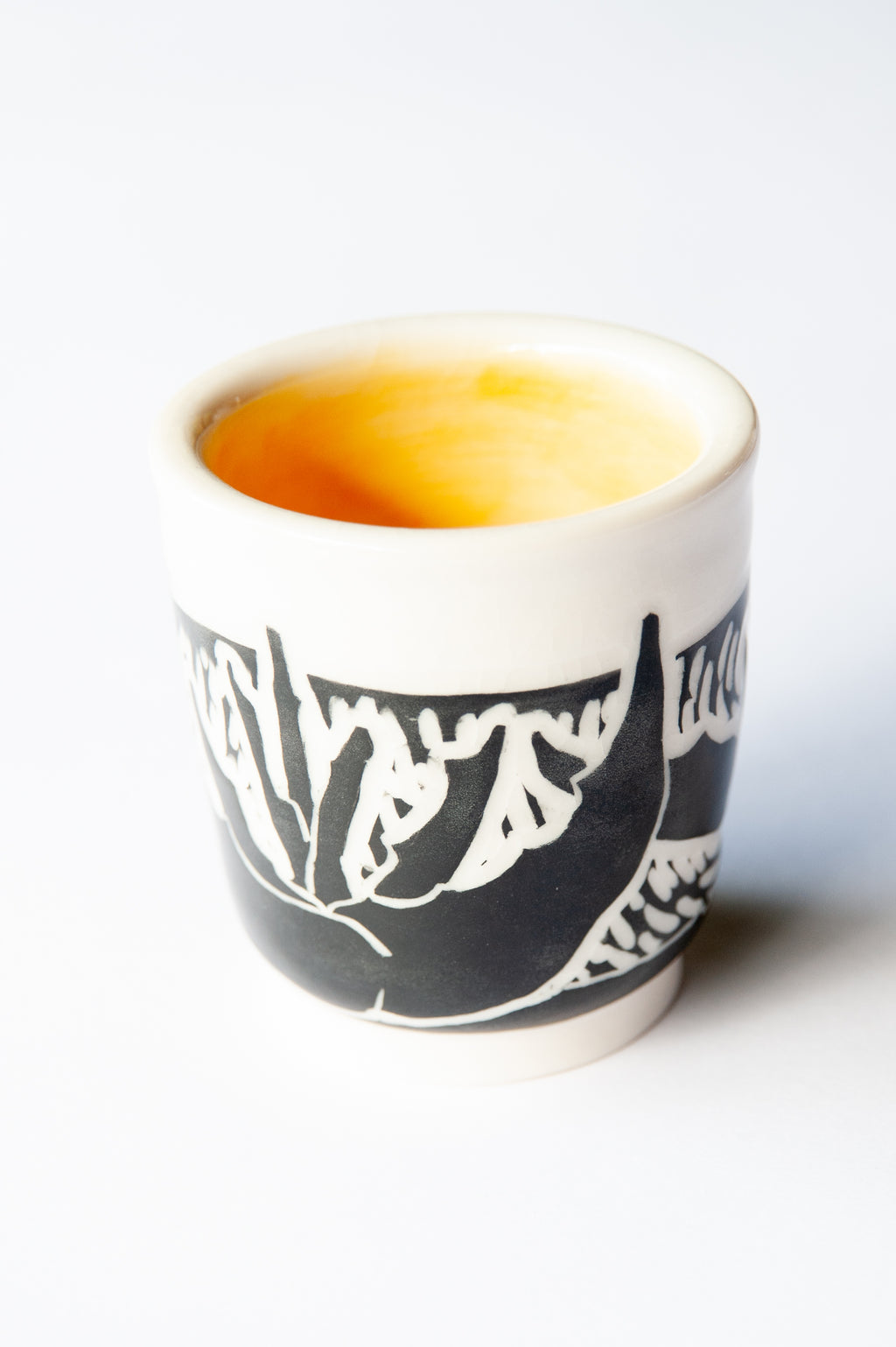 A small ceramic cup with a black and white agave block print design, set against a plain white background.