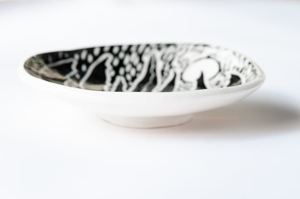 Profile of a black and white footed dish showing the foot and underside of the dish. 