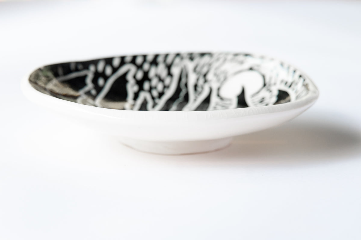 Profile of a black and white footed dish showing the foot and underside of the dish. 