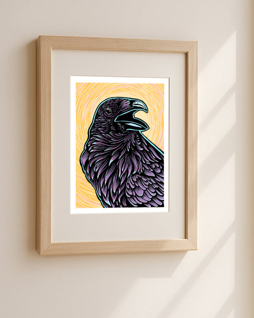 Framed artwork of a purple raven on a yellow background hanging in a white wall.