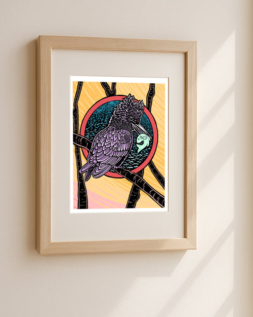 Framed artwork of a kingfisher with a fish in its mouth two birds flying against a colorful background hanging on a white wall.