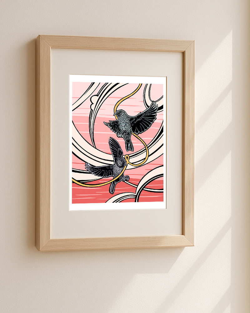 Framed artwork of two birds flying against a pink background hanging on a white wall.