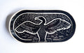 An oval black ceramic plate or tray featuring a carved image of a cormorant  with wings spread, set against a plain white background.