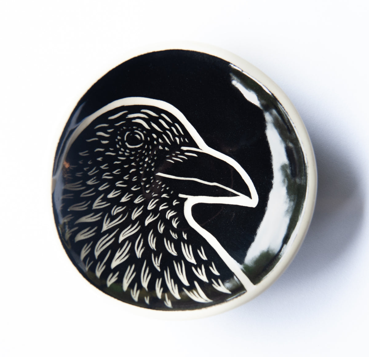 Round dish featuring an image of a crow in black and white.