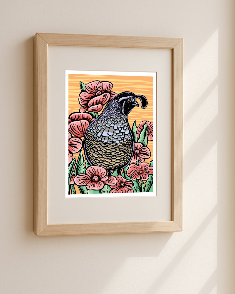 Framed art print of a quail surrounded by pink flowers on a warm orange background, displayed in a light wood frame on a beige wall in a natural wood frame with soft window shadows.