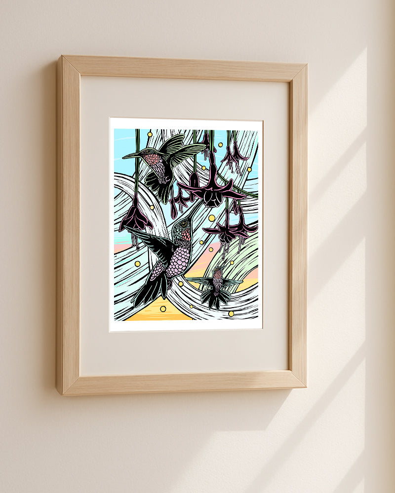 Framed artwork of hummingbirds and flowers hanging on a white wall.
