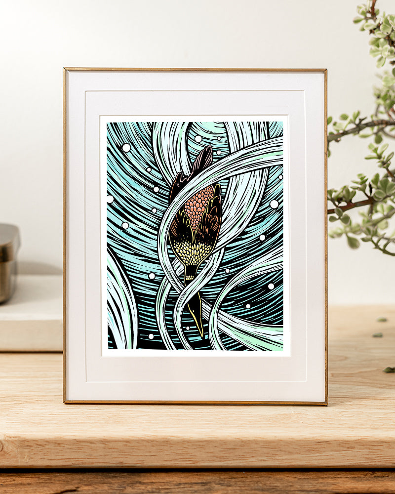 Framed artwork of a diving cormorant with abstract water background sitting on a desk.