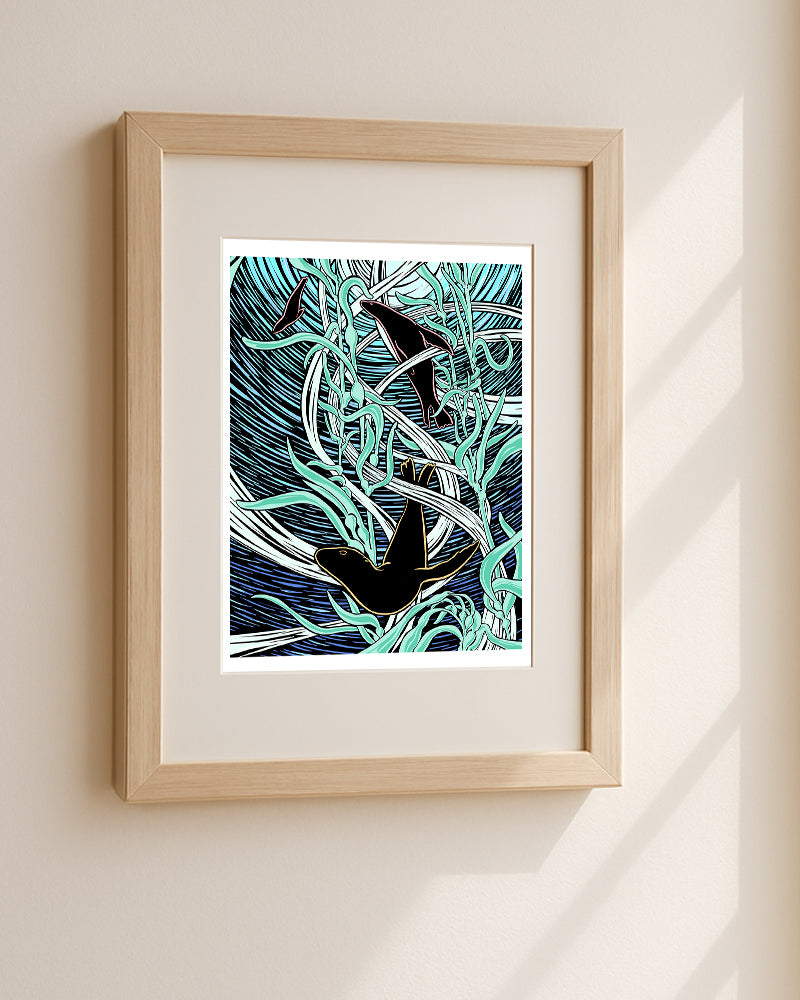 Framed artwork of sea lions frolicking in kelp hanging on a white wall.