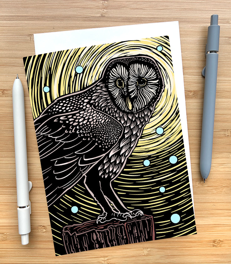Card with an owl illustration on a wooden surface with pens.