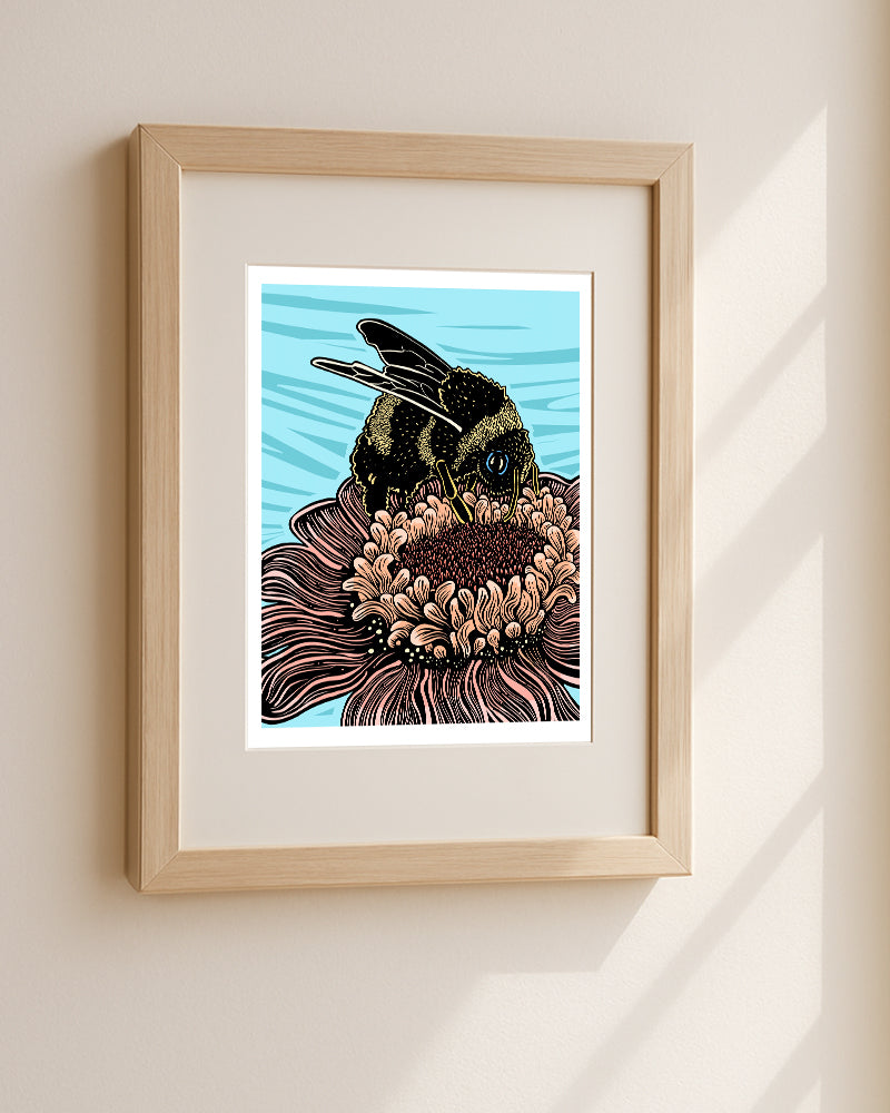 A framed art print featuring a detailed illustration of a bumblebee on a flower, mounted on a light beige wall with soft window shadows.