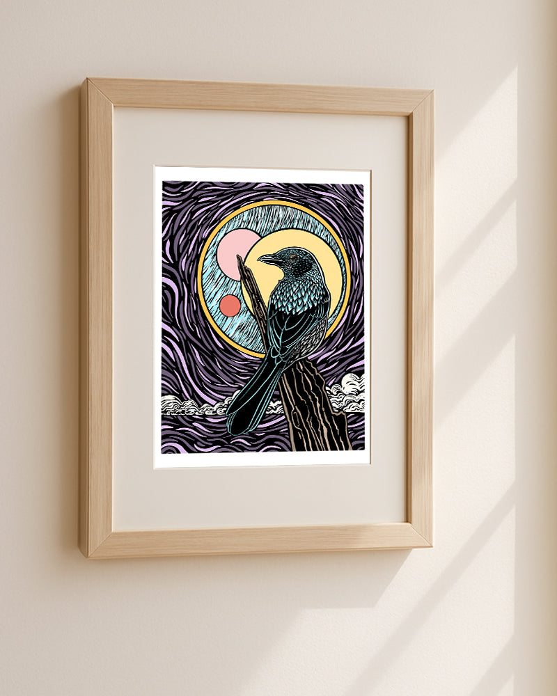 Framed artwork of a stylized bird on a branch with a colorful background on a beige wall.